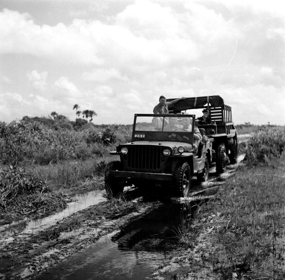Een jeep en een militair voertuig op een modderige weg bij Zanderij in Suriname, Bestanddeelnr 252-6360