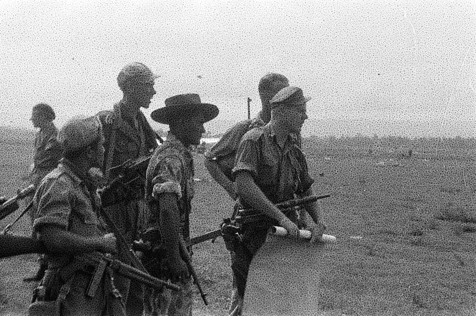 Een vijftal bewapende militairen waarvan de voorste een kaart oprolt op een vli, Bestanddeelnr 2360