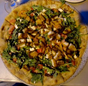 Pizza served for dinner with vegetables and chicken topping
