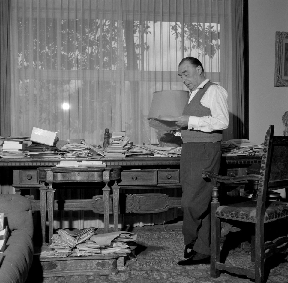 Remarque met een boek bij zijn schrijftafel in de villa in Porto Ronco, Bestanddeelnr 254-4730