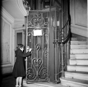 Meisje tijdens het openen van de liftdeur in het trappenhuis, Bestanddeelnr 252-9343