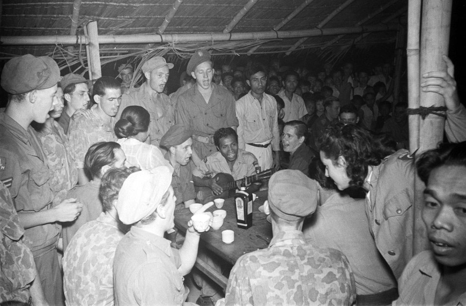 Nederlandse militairen in een barak. Een Indische militair bespeelt een gitaar, , Bestanddeelnr 85B-6-4