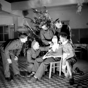 Nederlandse militairen rond een collega met kerstmanmasker die een sigaret rookt, Bestanddeelnr 255-9415