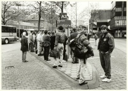 Wachtende buspassagiers op het Stationsplein, ziende naar het oosten. NL-HlmNHA 54032028