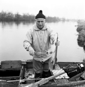 Vereniging Club der Honderd (vissen) een man staand in een roeiboot met een vi…, Bestanddeelnr 918-5693