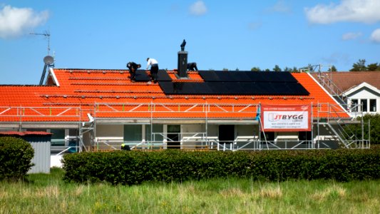 Three men installing solar panels on a house photo