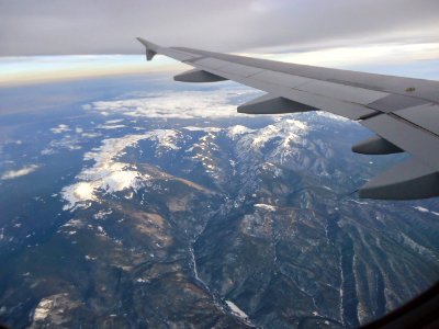 View from plane Rocky Mountains snowcapped peaks in March photo
