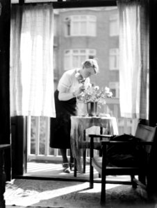 Vrouw schikt bloemen op het balkon, Bestanddeelnr 189-0408