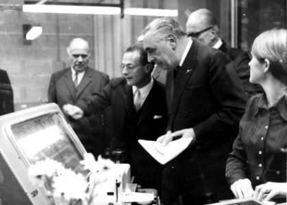 HUA-154496-Afbeelding van mr. M.G. de Bruin (president-directeur van de N.S.) die staatssecretaris M.J. Keyzer van Verkeer en Waterstaat rondleidt door het plaatskaartenkantoor tijdens de opening van de Traverse