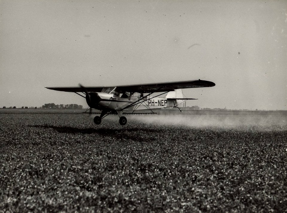 In de Houtrakpolder worden de veldgewassen, tegen schadelijke insekten, per vliegtuig bespoten. Aangekocht in 1977 van fotograaf C. de Boer. Identifcatienummer 54-004520
