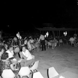 Terrasbezoekers bij het zwembad van het Avia-hotel bij avond, Bestanddeelnr 255-3098