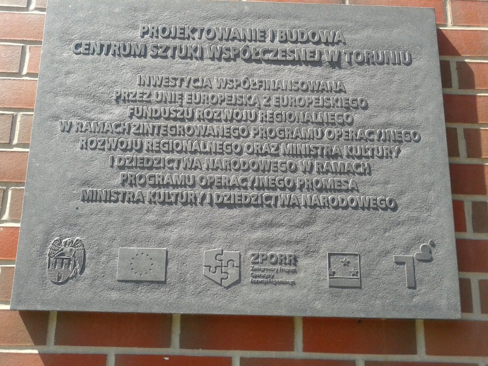 Tablica informacyjna na zewnętrznym filarze Centrum Sztuki Współczesnej Znaki Czasu