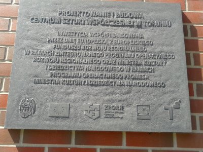 Tablica informacyjna na zewnętrznym filarze Centrum Sztuki Współczesnej Znaki Czasu
