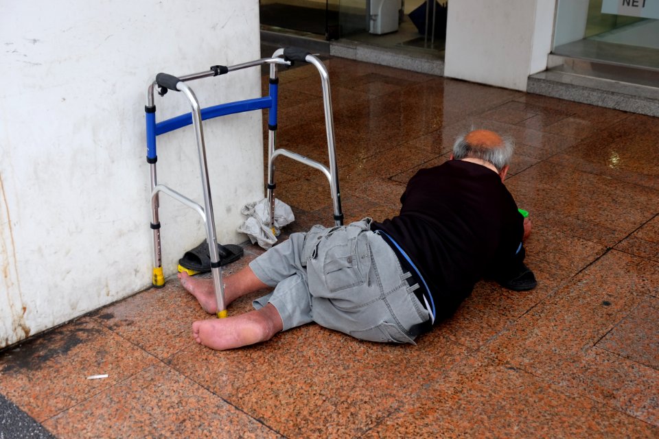 Old Beggar Lying on Arcade in Rainy Day 20170527