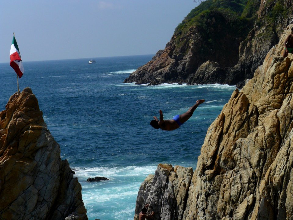 Clavadista y bandera mexicana en la Quebrada de Acapulco