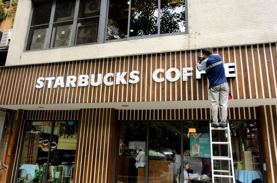 Worker on ladder renewing sign letters of Starbucks Taipei Sanmin Store 20150613