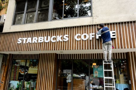 Worker on ladder renewing sign letters of Starbucks Taipei Sanmin Store 20150613