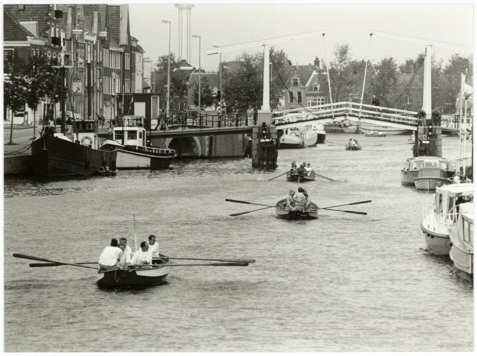 Roeiboten tijdens de vierde Waarderpolder Roeiregatta over het Spaarne waaraan 30 bedrijven deelnamen en die werd gewonnen door autosloopbedrijf Treffers. NL-HlmNHA 54035058