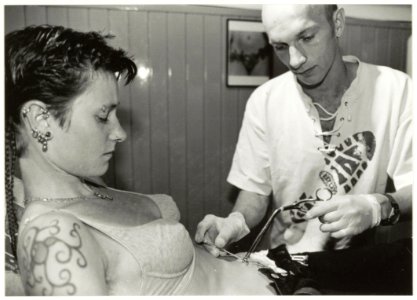 'Rings of pleasure' Piercing Studio in de Schagchelstraat. Foto Eigenaar Rob van Rijn plaatst een navelpiercing bij Saskia Harman. NL-HlmNHA 54037207