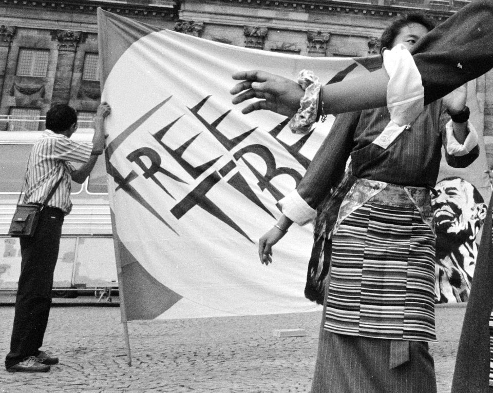 "FREE TIBET" flag with Tibetan women protesting the occupation of Tibet in Dam Square, Amsterdam on 26 July 1989, from- Protest op de Dam in Amsterdam van Tibetanen tegen de Chinese bezetting van Tibe, Bestanddeelnr 934-4865 (cropped)