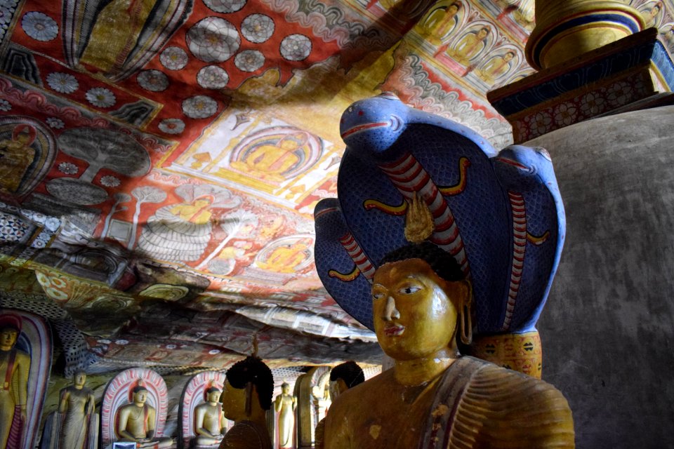 Buddha statue with blue cobra in the caves at Golden Temple in Dambulla