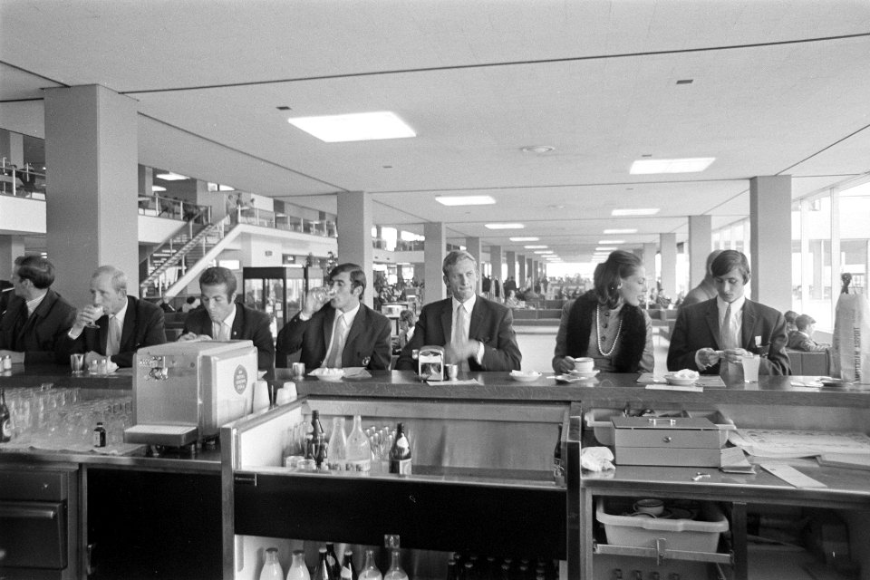 Enkele spelers zitten aan een bar tijdens het wachten op Schiphol, Bestanddeelnr 921-6832