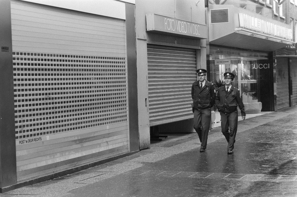 Gesloten rolluiken in Kalverstraat Amsterdam met patrouillerende agenten, Bestanddeelnr 934-0398