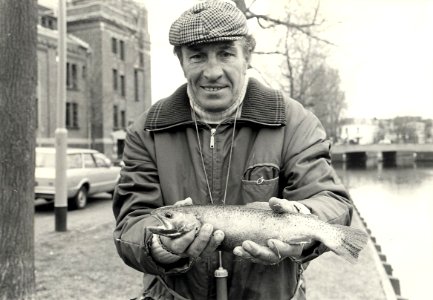 Gerrit van der Kuyl met zijn gevangen Forel, gevangen in de Leidsevaart ter hoogte van de Stadsschouwburg. Aangekocht in 1983 van United Photos de Boer bv. - Negatiefnummer 22833 k 9. - Gepu, NL-HlmNHA 54013834