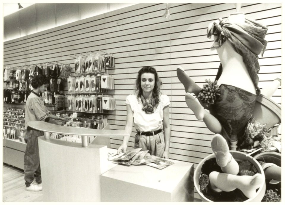 Ingrid van den Brink achter de toonbank van de speciaalzaak in panty's en sokken Mr. en Mrs. Legs. NL-HlmNHA 54031384