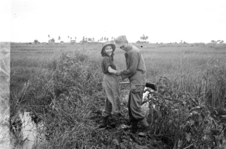 Indonesische man en meisje in uniform zitten samen in een veld. De man houd een , Bestanddeelnr 6084