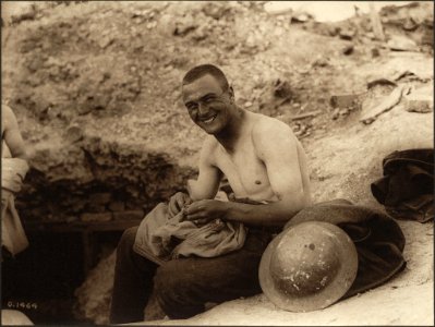 Soldier searching the seams of his shirt for lice photo
