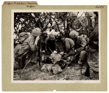Marines give first aid treatment to a wounded comrade as a… photo