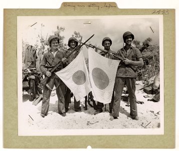 Coast Guard and Navy invaders display two Japanese flags w…