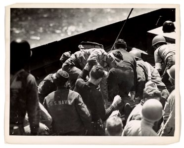 Coast Guardsmen turn to, helping the wounded soldiers from…