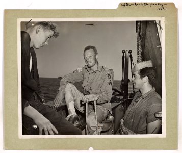 Two Coast Guardsmen hold a discussion with a wounded parat…