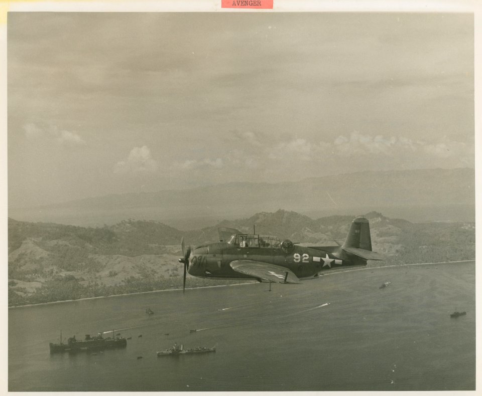 Grumman TBM Avenger flies above landing forces
