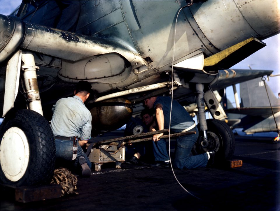 Aviation ordnancemen load bomb on underside of TBF.