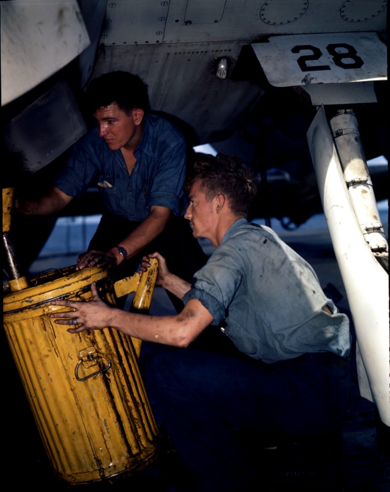 Aviation mechanics drain oil from engine of TBF.