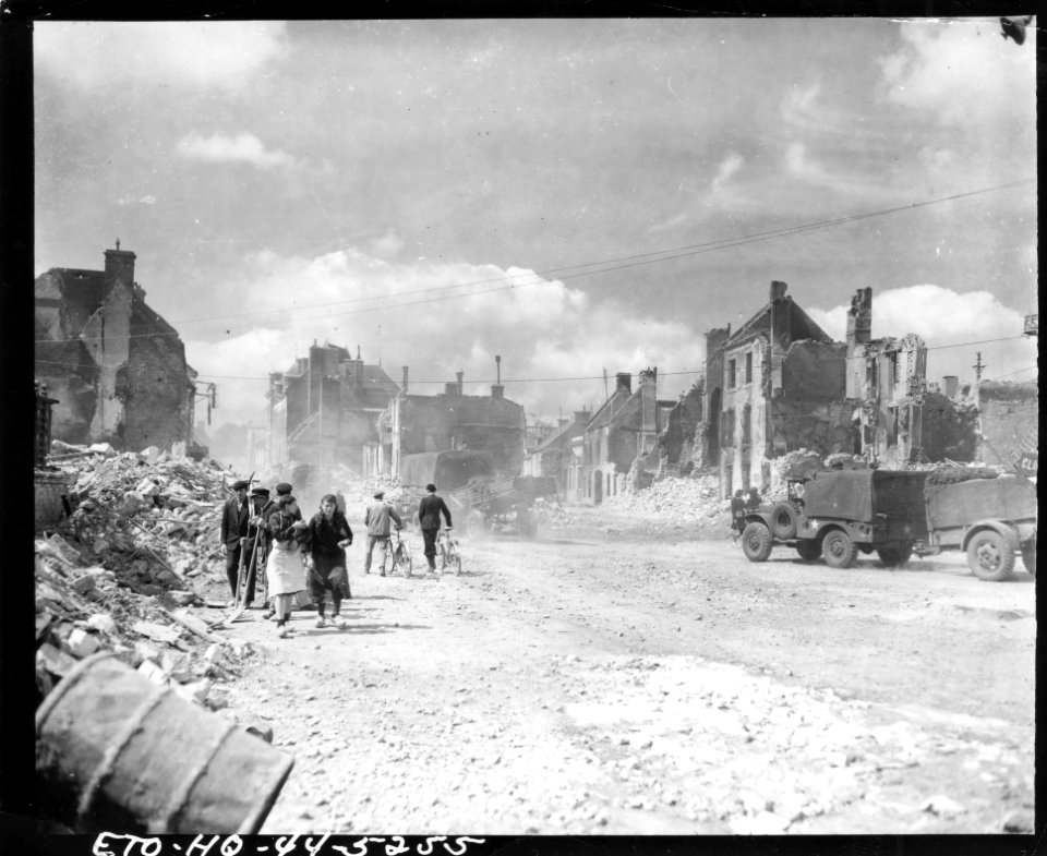 An American convoy passes through the streets of Carentan,…