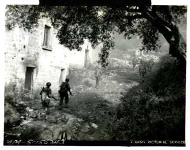 Alert Ranger riflemen advancing past a house on the Italia…