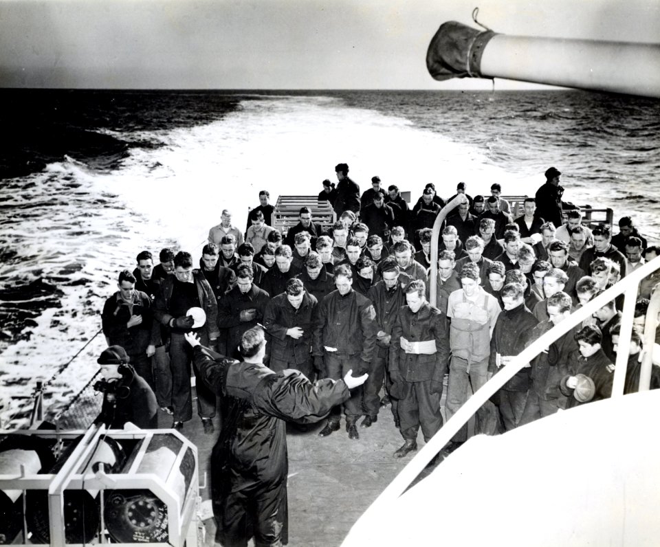 Enlisted men bow their heads as they follow the prayers of…