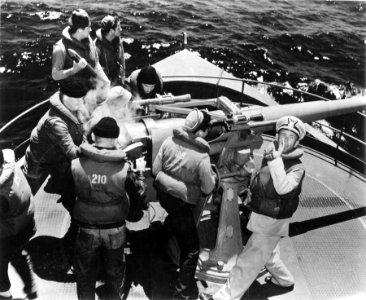 U.S. Coast Guardsmen man the forward gun on the bow of a C…
