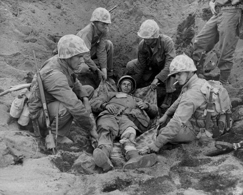 Marines carefully slide a poncho under Corporal W.H. Porte…