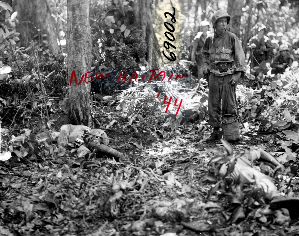 A Marine stands near the bodies of recently-killed Japanes…