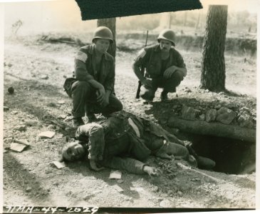 Two American infantrymen observing a dead Nazi sprawled on… photo