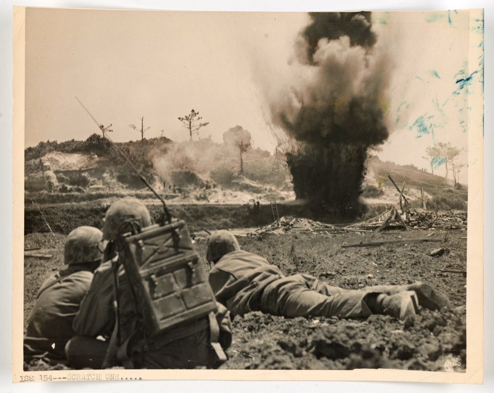 Sixth Marine Division Leathernecks, calmly watch as one of…