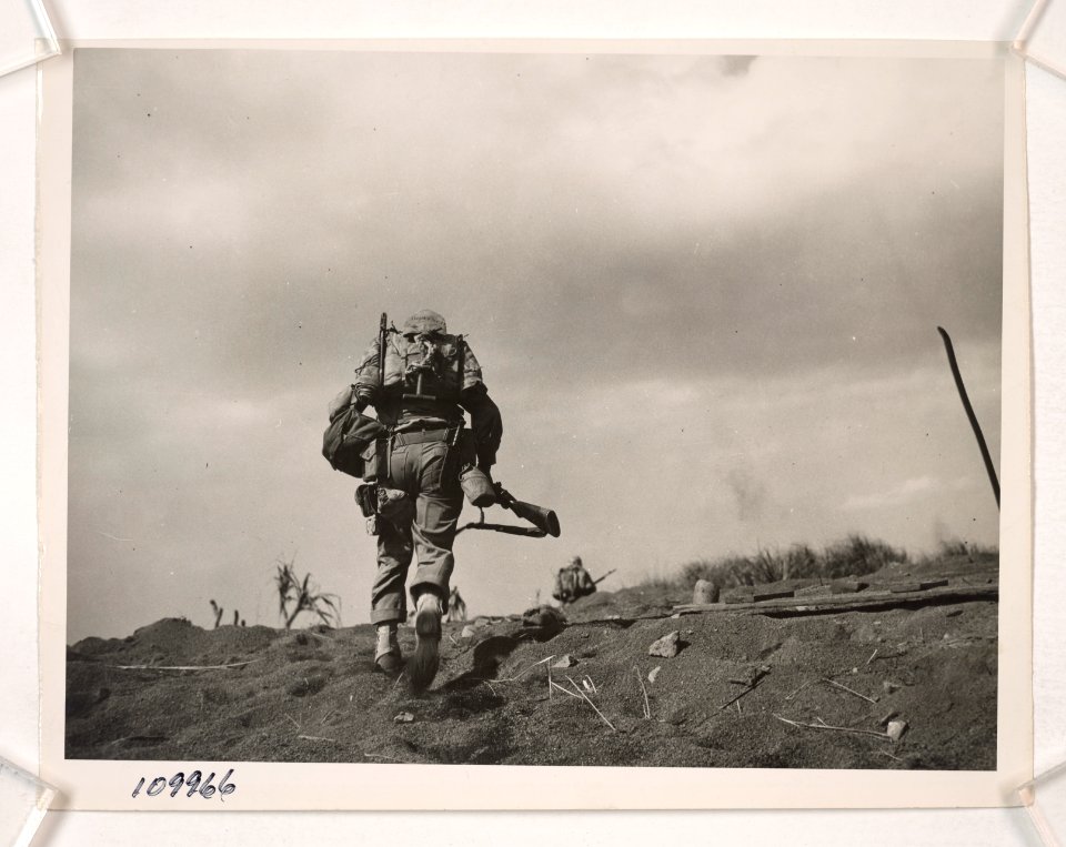 In full battle gear, a Marine of the Fifth Division tops a…