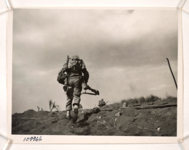 In full battle gear, a Marine of the Fifth Division tops a…