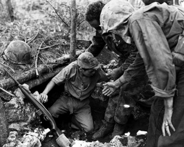 U.S. Marines help a Japanese soldier from a dugout on Tini…