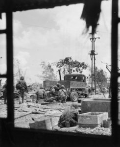 Viewed through the window of a wrecked building, a Marine …